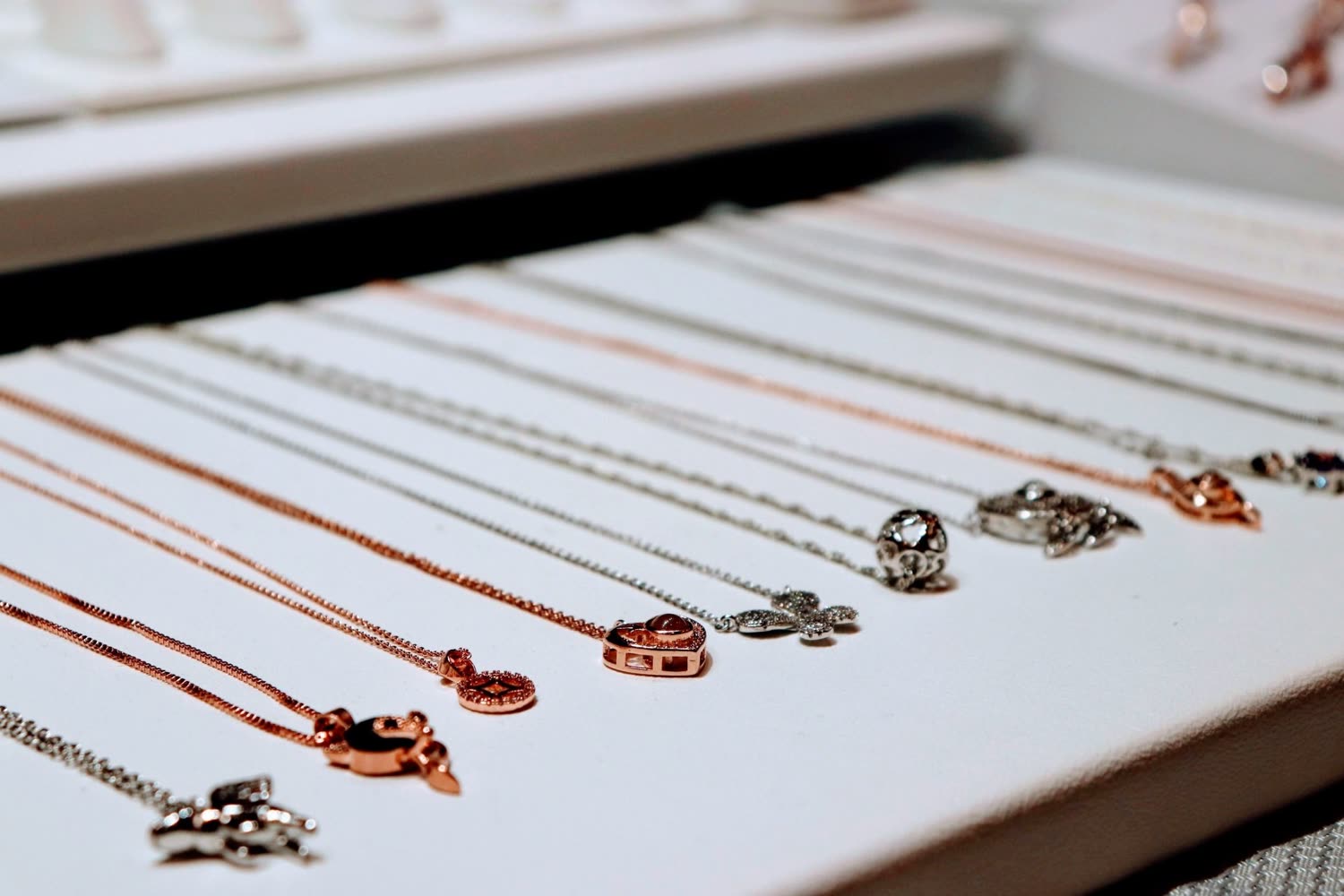 Fine silver charm necklaces on a white display
