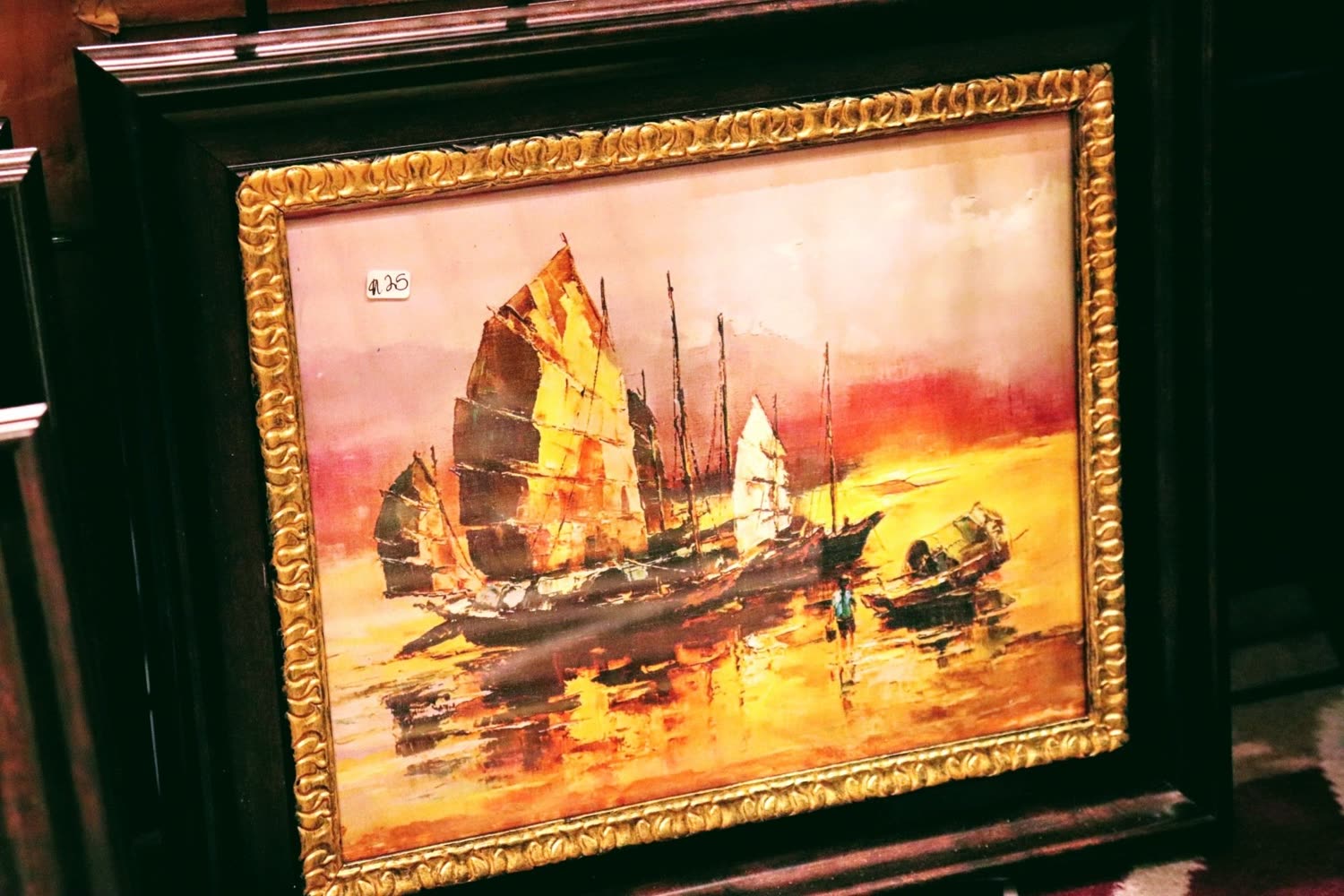 A framed painting of junk boats at sunset